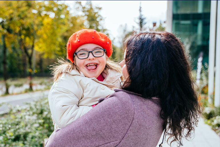 Cute little girl in a red beret with special needs enjoy having fun spending time with mother outdoor in autumn time